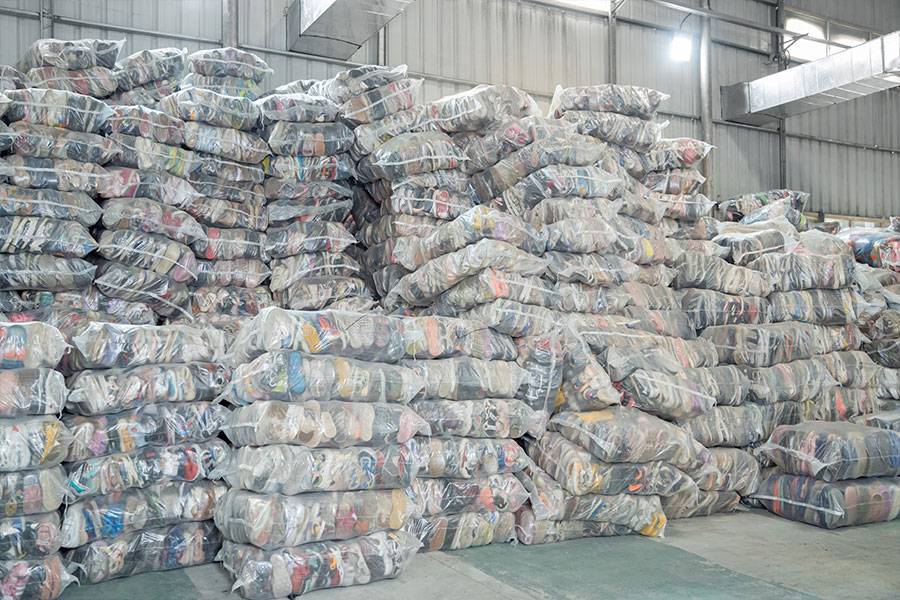 stacks of bales filled with used branded shoes