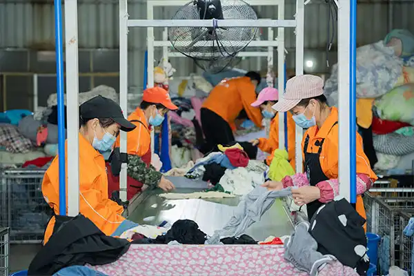 team going through used clothes lined up on an assembly line