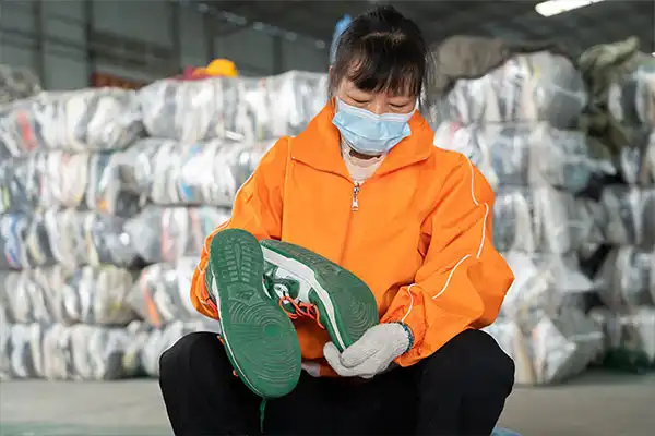 sorter looking at the soles of a used shoe pair