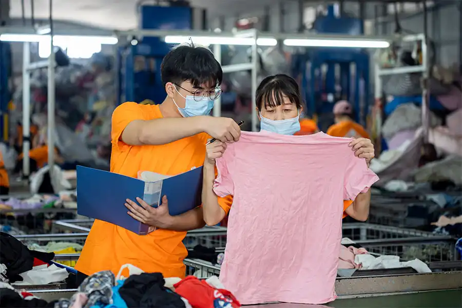 sorters checking the condition of a pink used shirt