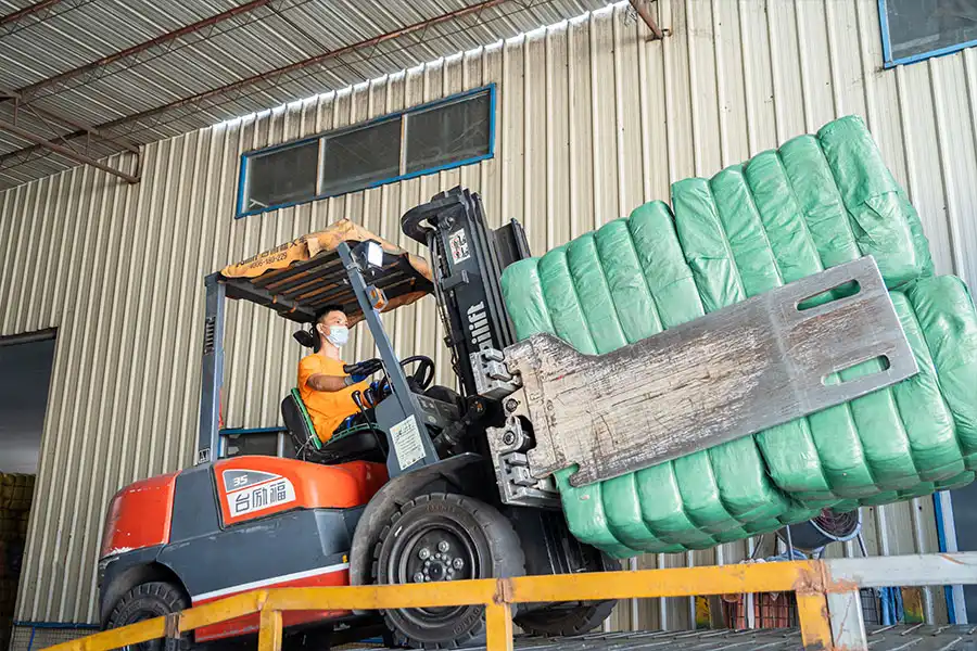 forklift taking the used clothing bales from the cargo truck