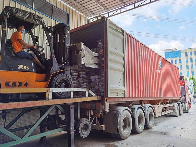 forklift operator in the process of loading container with used clothing bales