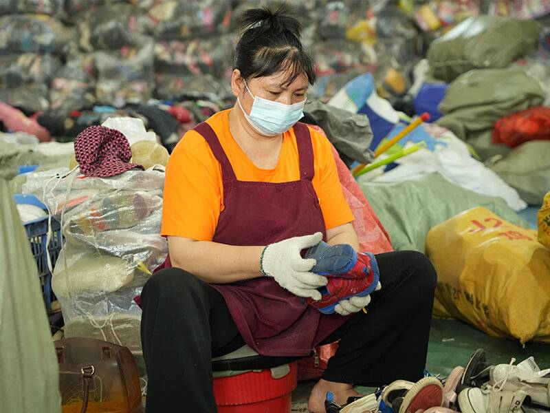 female worker in an apron inspects a used branded shoe