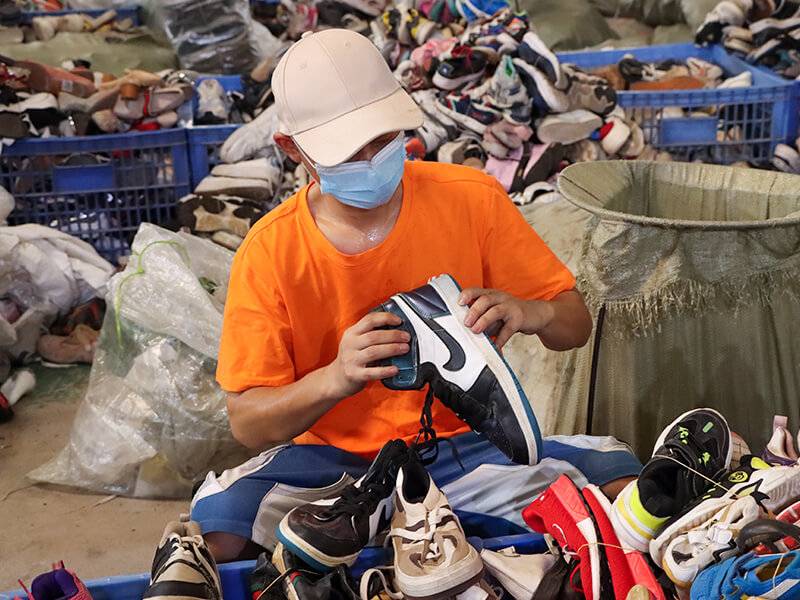 male sorter going through pieces of used branded shoes