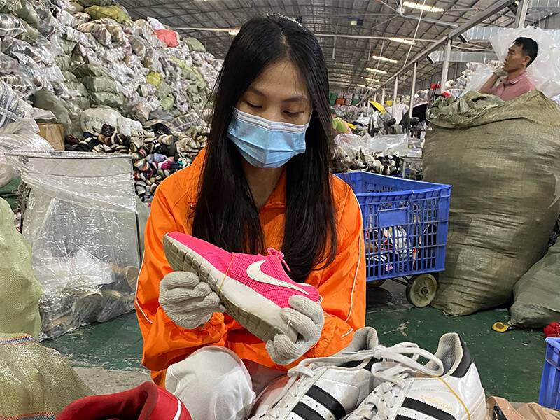 female sorter scanning a used branded shoe for damage
