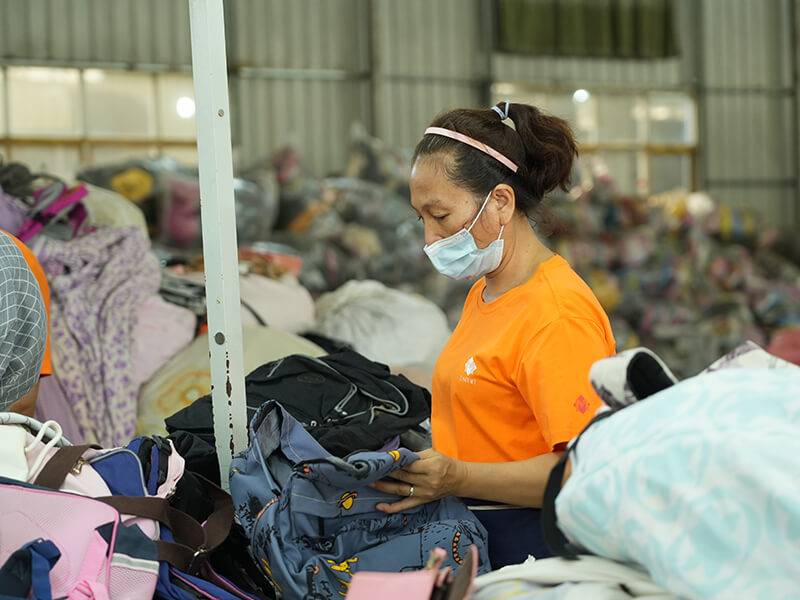 sorter handpicking an item from a pile of top-grade used clothing