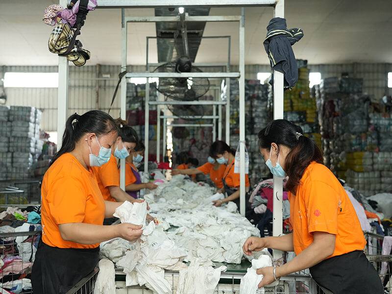 sorters go through numerous used clothing on an assembly line